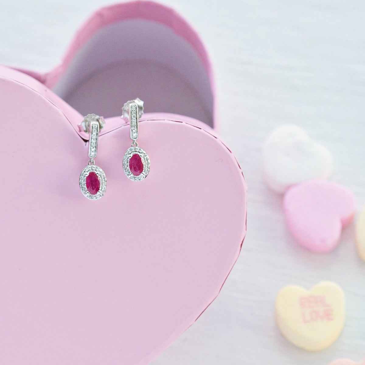Genuine Oval Ruby Fashion Earrings with 1/10 ct. tw. Diamond Halo & Bail with Milgrain Edging in 10K White Gold front view